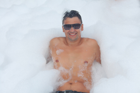 the man in glasses has fun in the white foamの写真素材