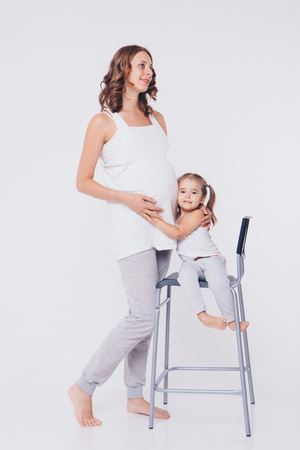 Happy kid girl hugging pregnant mother's belly, pregnancy and new life conceptの写真素材