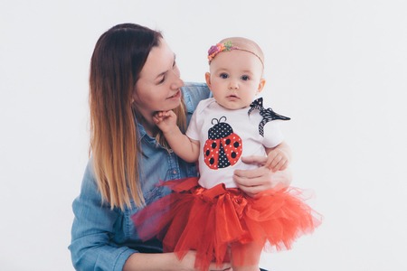 baby in the arms of the mother. on white background Woman holding a child. Fashion for girl.の写真素材
