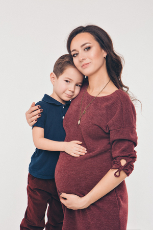 Happy kid girl hugging pregnant mother's belly, pregnancy and new life conceptの写真素材