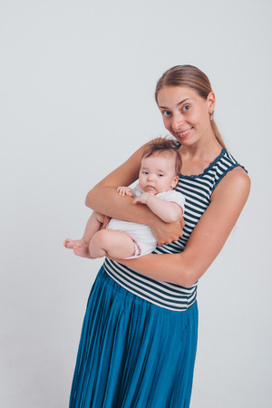 baby in the arms of the mother. on white background Woman holding a child. Fashion for girl.の写真素材