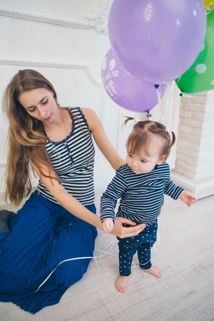 the child in the arms of his mother on a white background. A woman with a child in her arms holding festive balloonsの写真素材