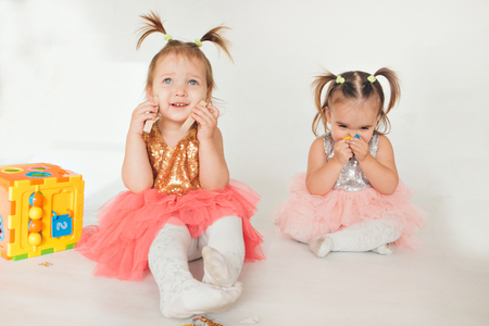 two little girls playing on the floor on a white backgroundの写真素材