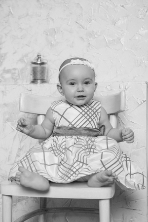a little girl in a dress sits on a chair and smilesの写真素材