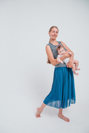 baby in the arms of the mother. on white background Woman holding a child. Fashion for girl.の写真素材
