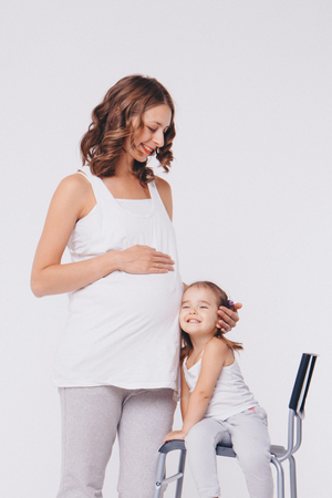 Happy kid girl hugging pregnant mother's belly, pregnancy and new life conceptの写真素材