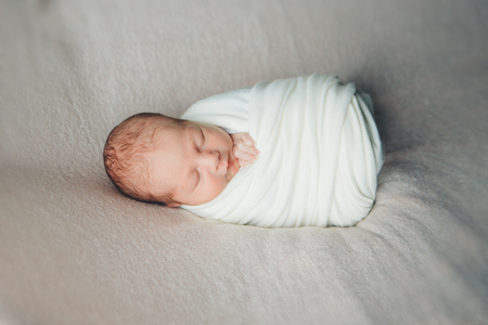 newborn baby sleeps wrapped in a blanketの写真素材