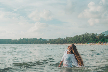 girl with long hair in white shirt posing in waterの写真素材