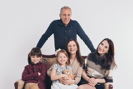 group of people on a white background: adults and children with toys sitting on the same couchの写真素材