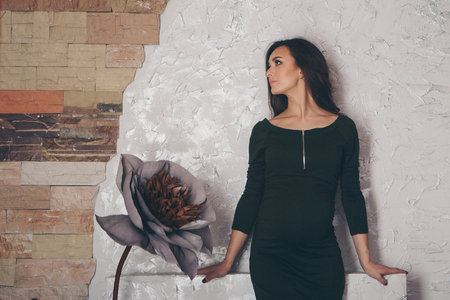 March 8: beautiful pregnant girl with long hair next to a huge artificial flowerの写真素材