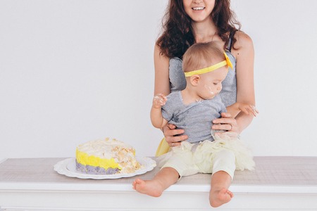 the child in the arms of his mother, who was soiled with food. A woman with a child in her arms eating cakeの写真素材