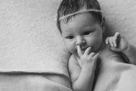 portrait of a newborn baby with a pen on his face: a finger in his noseの写真素材