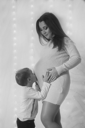Happy kid girl hugging pregnant mother's belly, pregnancy and new life conceptの写真素材