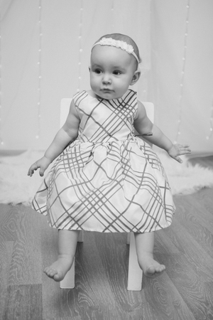 a little girl in a dress sits on a chair and smilesの写真素材