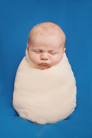 newborn baby sleeps wrapped in a blanketの写真素材