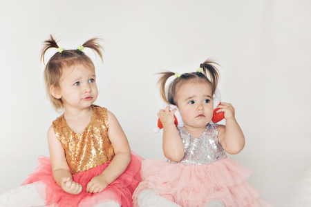 two little girls playing on the floor on a white backgroundの写真素材