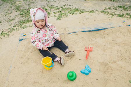 Little girl sitting in the sandbox and playing with the mold on the Playground little kid playing in the sandの写真素材