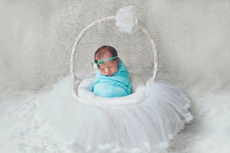 newborn baby wrapped in a blanket sleeping in a basketの写真素材