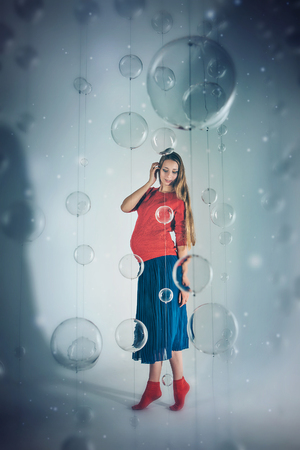 the view from the top: pregnant woman on white background with glass balls. Woman in red and blue clothesの写真素材