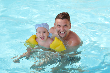 a man with a child swimming in the pool. Dad with daughter in the waterの写真素材