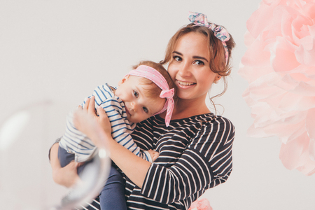 the child in the arms of his mother on white background. A woman with a child in her arms next to a large flowerの写真素材