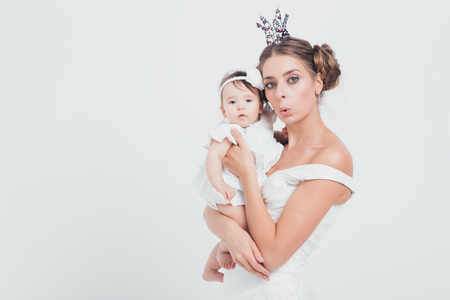 baby in the arms of the mother. on white background Woman holding a child. Fashion for girl. Queen with princessの写真素材