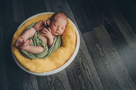 newborn baby wrapped in a blanket sleeping in a basketの写真素材