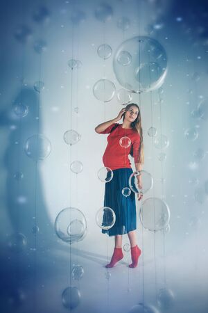 the view from the top: pregnant woman on white background with glass balls. Woman in red and blue clothesの写真素材