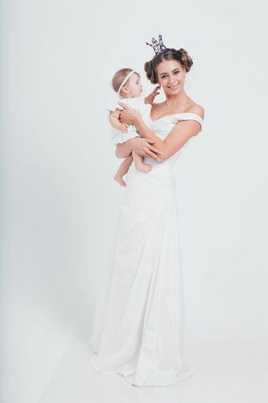 baby in the arms of the mother. on white background Woman holding a child. Fashion for girl. Queen with princessの写真素材