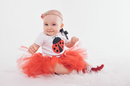 a little girl in a dress sits on the floor on a white background. Child promotes childrens clothesの写真素材