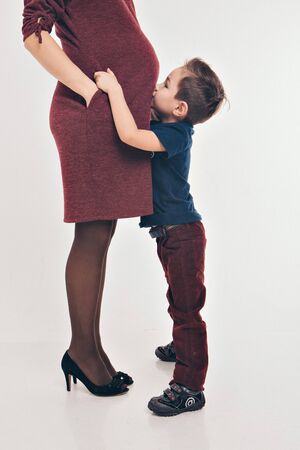 Happy kid girl hugging pregnant mother's belly, pregnancy and new life conceptの写真素材