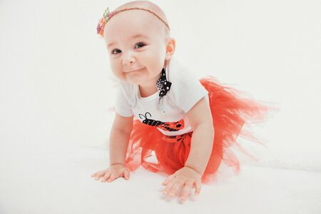a little girl in a dress sits on the floor on a white background. Child promotes childrens clothesの写真素材