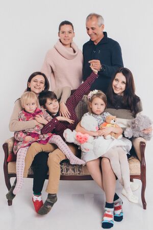 group of people on a white background: adults and children with toys sitting on the same couchの写真素材