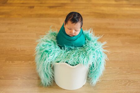 newborn baby wrapped in a blanket sleeping in a basketの写真素材
