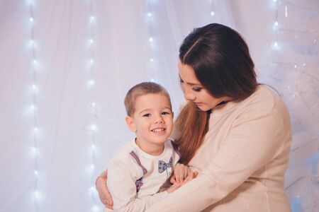 the child in the arms of his mother on the background of lights and decorative elementsの写真素材