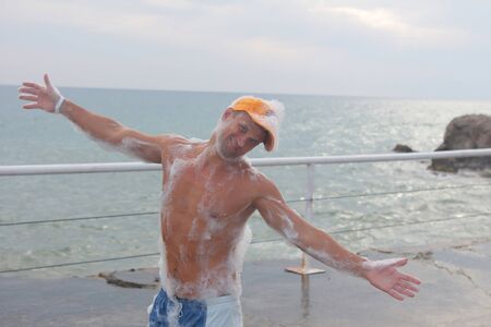 guy with glasses having fun in white foam. the man on the beach among the raging wavesの写真素材