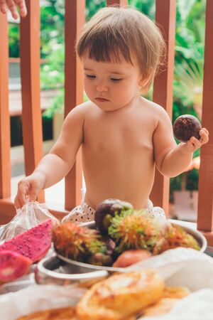small Caucasian child eating exotic fruits handsの写真素材