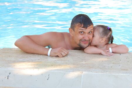 a man with a child swimming in the pool. Dad with daughter in the waterの写真素材