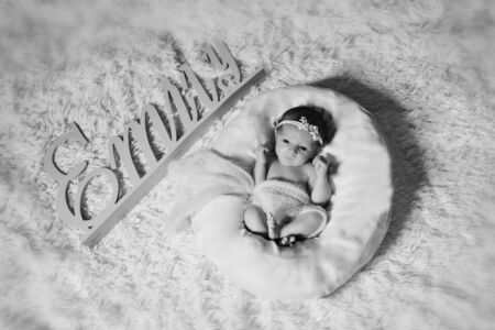 a newborn baby with a flower bandage on his head, wrapped in a blanket, sleeping in a basket. Emily's name plateの写真素材