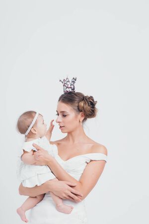 baby in the arms of the mother. on white background Woman holding a child. Fashion for girl. Queen with princessの写真素材