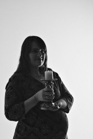 a pregnant girl holds a candlestick in her handsの写真素材