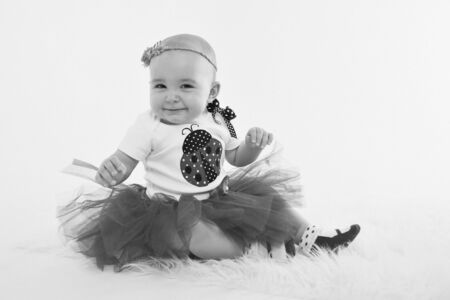 a little girl in a dress sits on the floor on a white background. Child promotes children's clothesの写真素材