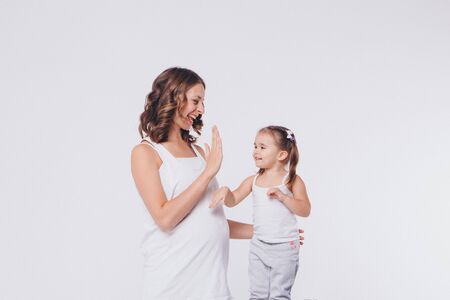mother and daughter slapped each other's hands. Pregnant woman and child negotiate on white backgroundの写真素材
