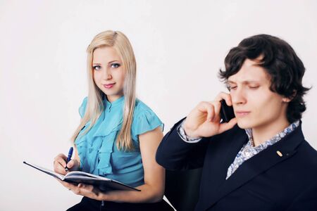 portrait of 2 students on a white background. A man talking on the phone, a woman writes in a notebookの写真素材