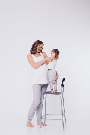 mom and daughter having fun on a white background. Pregnant woman and child play togetherの写真素材