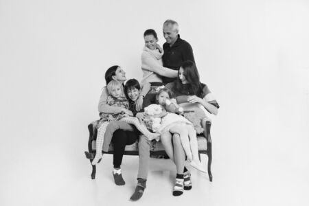 group of people on a white background: adults and children with toys sitting on the same couchの写真素材