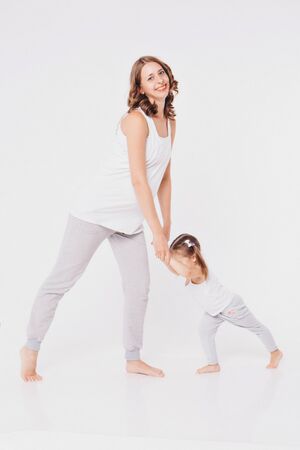 happy family engaged in recreational gymnastics. A pregnant woman are sitting on the floor. Isolated on white backgroundの写真素材