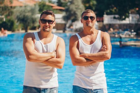 the concept of recreation, tourism - two smiling inflated men with glasses having fun by the poolの写真素材