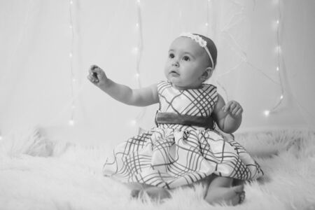 the concept of a healthy lifestyle, the protection of children, shopping - a little girl in a dress sits on the floor on a white background. Child promotes children's clothesの写真素材