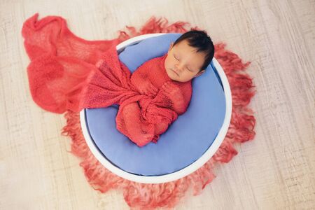 newborn baby wrapped in a blanket sleeping in a basket. concept of childhood, healthcare, IVFの写真素材